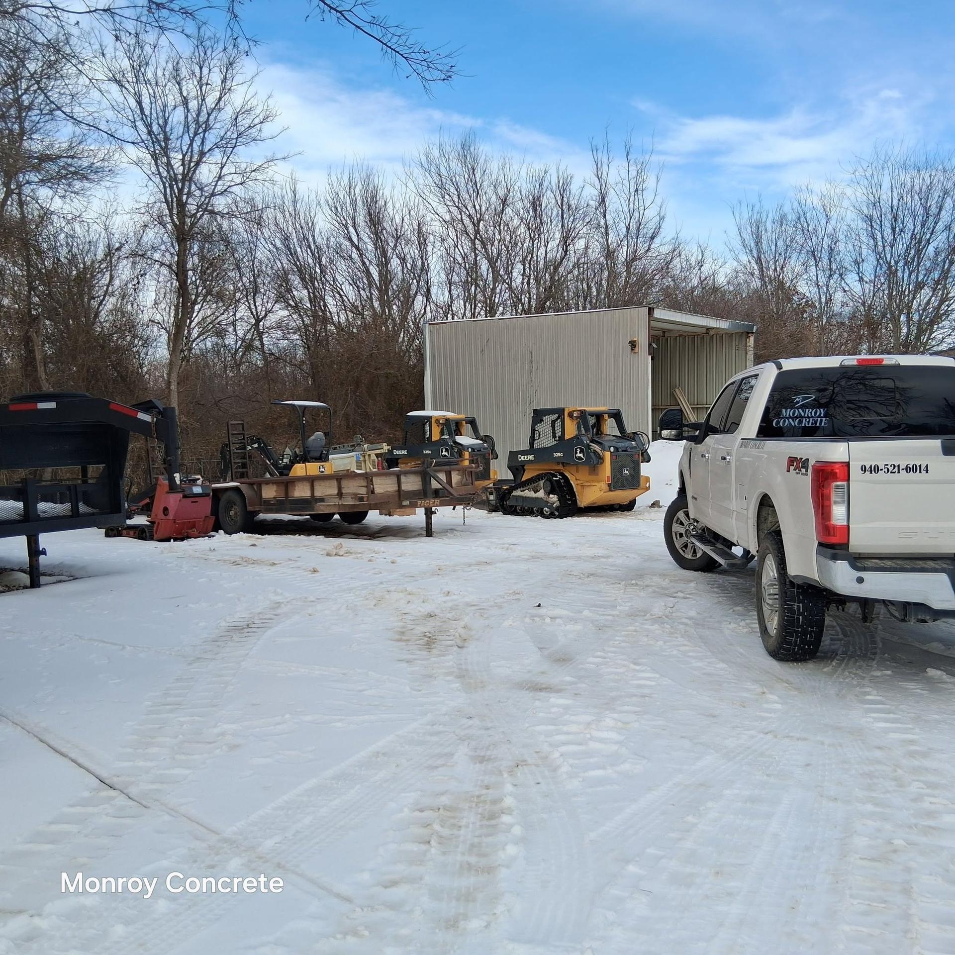 Monroy Concrete truck and skid steer loaders parked in the equipment yard after a snowfall