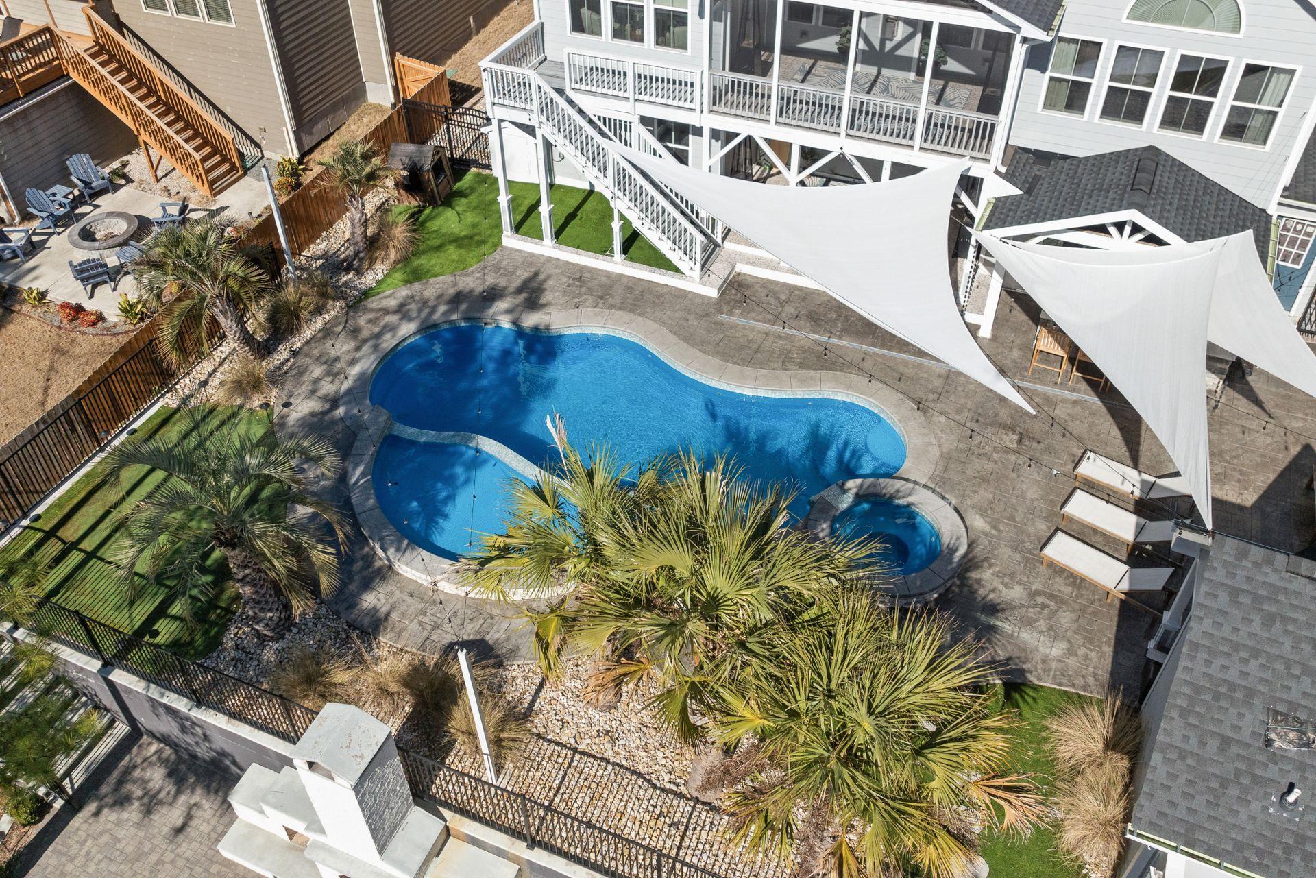 Aerial view of a curved concrete pool deck surrounding a backyard swimming pool